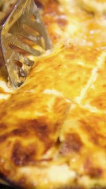 Bir parça İtalyan lazanyasını spatulayla yakın plan çekiyoruz. Beşamel soslu lazanya, mozzarella ve bolonez. Fırın tepsisindeki lazanya.
