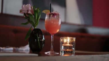 Barmen mumlarla dolu bir barda kokteyl hazırlıyor. Alkol, bar tezgahı, otel, mum zarafeti, eğlence, eğlence, eğlence ve modaya uygun projeler için harika. Cam, kokteyl, gece, mum, çiçekler.
