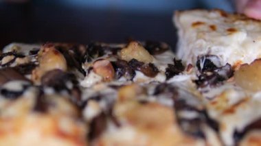 Aşçı bir dilim pastırma, mantar ve peynirli pizza alır. Lastik eldiveni yakın plan çek. Tahtada mantarlı pizza.