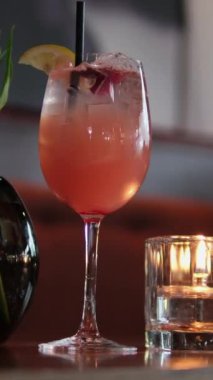 Barmen mumlarla dolu bir barda kokteyl hazırlıyor. Alkol, bar tezgahı, otel, mum zarafeti, eğlence, eğlence, eğlence ve modaya uygun projeler için harika. Cam, kokteyl, gece, mum, çiçekler.
