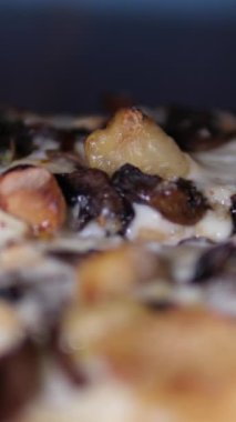 Aşçı bir dilim pastırma, mantar ve peynirli pizza alır. Lastik eldiveni yakın plan çek. Tahtada mantarlı pizza.