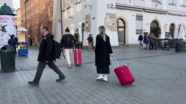 Çantalı turistler Krakow tarihi pazar meydanı, Polonya, Orta Avrupa. Pazar Meydanı Krakow, Polonya 'nın eski Krakow kentinin merkez meydanıdır.