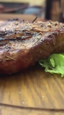 Şefin orta veya iyi pişmiş biftek dilimlemesi bıçak ve çatalla ahşap kesim tahtası veya kesim tahtası, 4K. Et ve biftek kavramı. Yüksek kalite 4k görüntü