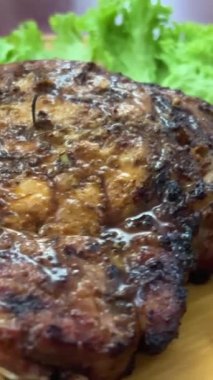 Kaburgaları yuvarlak bir tahta kesme tahtasının üstünde ızgarada pişirilmiş döner tabak. Tahtada biftek.