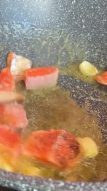 Ekstra lezzet için üzerine tereyağlı ve sarımsaklı karanfilli tavada kızartılmış iki somon filetosu genel görünümü. Kızartma tavasında somon parçaları