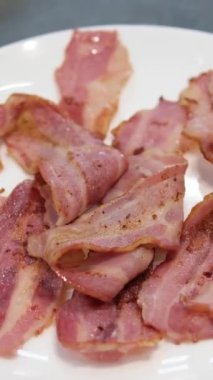 Dökme demir bir tavada yağla kızartılmış lezzetli domuz pastırması görüntülerini kapatın. Parlak, aromatik, kızgın tavada kıtır kıtır pastırma parçaları. Yüksek kalite 4k görüntü