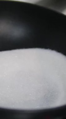 Kızartma şekeri hızla yanan bir tavada erir ve tahta kaşıkla karıştırılarak karamelaya dönüşür. Yüksek kalite 4k görüntü