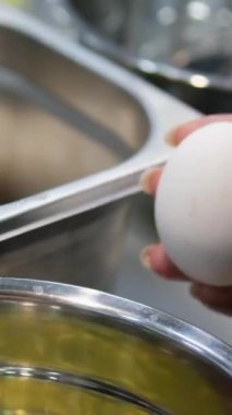 Kadın elleri cam bir kaseye yumurta kırıyor. Mutfakta yumurtalarla yemek pişiren kadın ellerini yakından izleyin. Yüksek kalite 4k görüntü