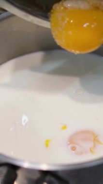 Süt, yumurtayla kaseye akıyor, ağır çekimde. Hamur hazırlığı. Şef cam bir kaseye süt döker. Süte sarısı ekle