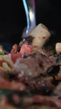 Gecenin geç saatlerinde bir restoranda, et mantarlı ve sebzeli makarna ve çatal-bıçak al. Yüksek kalite 4k görüntü