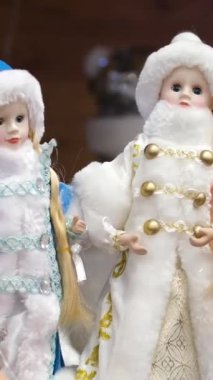 Biri mavili, diğeri altın elbiseli iki Kar Kızı oyuncağı. Bir kız mağazadan Noel ağacının altında hediye seçiyor. Kışlık şapkalı ve mantolu güzel bir kız. Yüksek kalite 4k görüntü