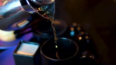 Koyu bir restoranın siyah bardaklarına çay doldurmak çay yapma sürecinin üç videosu. Yüksek kalite 4k görüntü