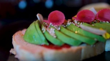 Tahta kesme tahtasında lezzetli avokado sandviçleri. Atıştırma. Avo tostu, sriracha, karpuz turpu, parmak limonu, kızarmış tohumlar. avokado sandviçi