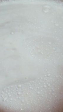 Süt metal bir tavada kaynıyor. dikey video, yüksek kalite 4k görüntü