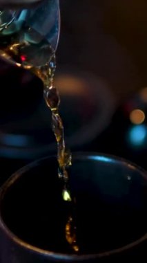 Koyu bir restoranın siyah bardaklarına çay doldurmak çay yapma sürecinin üç videosu. Yüksek kalite 4k görüntü