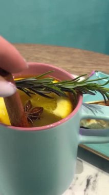 Biberiye portakallı dilimler tarçın dikenli deniz dikenli mango turkuaz bardakta lezzetli sıcak çay ve tatlı fıstıklı cheesecake turtası. Yüksek kalite 4k görüntü