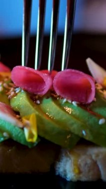 Adam lezzetli avokado tostu hazırlıyor. Eller kızarmış çavdar ekmeğine avokado püresi döker. Tepeden. Avo tostu, sriracha, karpuz turpu, parmak limonu, kızarmış tohumlar. avokado sandviçi