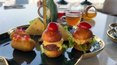 Öğle yemeği mini burgerler siyah çay tabağında altın yapraklı şık restoran lüks oteli. Yüksek kalite 4k görüntü