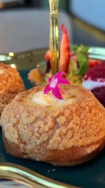 Yüzüklü mini choux hamur işleri kızı maket tabağından, sepet ve kırmızı kadife kekin yanındaki yenilebilir çiçekli pastaları alır. Yüksek kalite 4k görüntü
