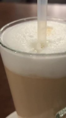 Güzel bir cappuccino kahve bardağına cam tüp sokuyorum. Güzel bir cam bardak balkonda ya da terasta bir masanın üzerinde duruyor. Keyifli bir boş zaman geçir. Pipetle kapuçino.