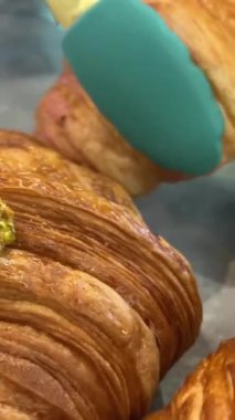 Sıcak bir fırının içinde, cam bir kubbenin altında glütensiz kruvasan sunan bir kadın, sağlık bilinci olan müşteriler için glütensiz seçeneği vurguluyor. Yüksek kalite 4k görüntü