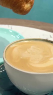 Sıcak çıtır kruvasanı cappuccino 'ya bandırıyorum. Mutfak fırınında ev yapımı el yapımı tatlı. Sabah Ev Yapımı Kahvaltı. Kahvaltıda Lezzetli Fransız kruvasanı. Aperatif Fırın Crunch Kruvasan.