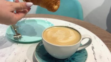 Sıcak çıtır kruvasanı cappuccino 'ya bandırıyorum. Mutfak fırınında ev yapımı el yapımı tatlı. Sabah Ev Yapımı Kahvaltı. Kahvaltıda Lezzetli Fransız kruvasanı. Aperatif Fırın Crunch Kruvasan.