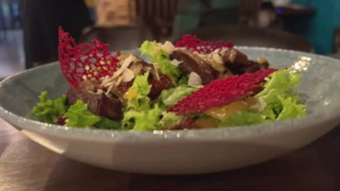 Lezzetli taze sezar salatası siyah bir masada döner. kırmızı dantel süslemeler tabakta yenilebilir