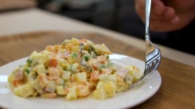 Geleneksel Olivier salatası. Noel ve Yeni Yıl yemekleri. Çatallı beyaz tabak ve arka planda bıçak ve fotokopi alanı. Üst manzara, düz yatış. Mikro yeşil, bıldırcın yumurtası. Bir restoranda hizmet etmek.. 