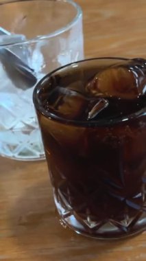 Kola 'ya buz ekle. Buzlu kolayı, ceviz masasında, cam küplerin üzerine dök. Metin için de yer olsun. Yüksek kalite 4k görüntü