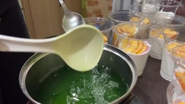 Ev yapımı jöle yapma işlemi. Plastik bardaklarda porsiyonlar halinde. Meyveli farklı katmanlar halinde jelatin dökülüyor. Yüksek kalite 4k görüntü