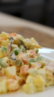 Geleneksel Olivier salatası. Noel ve Yeni Yıl yemekleri. Çatallı beyaz tabak ve arka planda bıçak ve fotokopi alanı. Üst manzara, düz yatış. Mikro yeşil, bıldırcın yumurtası. Bir restoranda hizmet etmek.. 