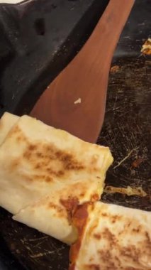 Sulu peynirli lavaşlı Shawarma siyah tabakta servis edilir. Köy evinde eski bir tavada peynirli lavaş kızartmak yemek pişirmek.