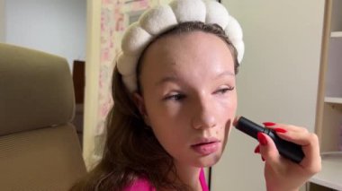 Kaplama, bronzlaştırıcı makyaj malzemesi. Güzel bir genç kadının portresi pürüzsüz bir cilt ve taze makyaj ve fırçayla yapılmış eller makyaj, dış hatlar ve kadın yüzü..