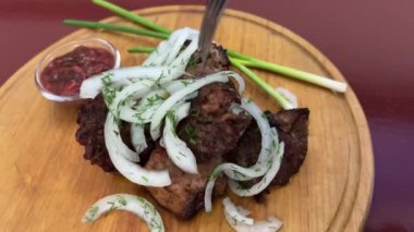 Bir adamın ellerinin bir parça ızgara eti kremalı sosa batırdığı yakın plan bir fotoğraf. Lokantada lezzetli et yemekleri yeme fikri. Yüksek kalite 4k görüntü