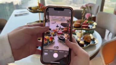Kahve dükkanında yemek fotoğraflayan çekici genç bir kadın. Kapatıyoruz. Yüksek kalite 4k görüntü