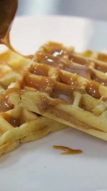 Tatlı akçaağaç şurubuyla serpiştirilmiş gevrek, altın waffle 'ların yakın makro görüntüsü. gözlemelerin üzerine karamel serpiştir