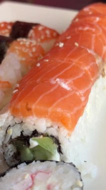 Çeşitli suşi ruloları ve tabakta nigiri, iştah açıcı yemeklerde geleneksel Japon mutfağı. Japon yemeği ve mutfağı. Üzerine siyah susam tohumu serp.