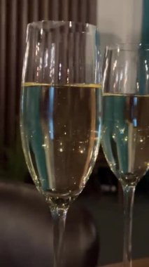 Sıranın üzerinde duran bir kadeh şampanya. Şampanya köpükleri. Yavaş çekim ve küçük hava kabarcıklarının makro sabit çekimi zarif bir şampanya bardağında güneş ışığına karşı yukarıya doğru akıyor. Yüksek kalite 4k