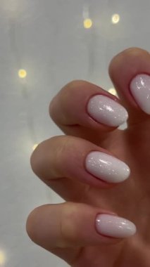 Güzel yeni yıl beyaz oval manikürü beyaz bir çelenk duvarının arka planında. Güzellik salonu, manikürcü, genç bayan eli. Yüksek kalite 4k görüntü