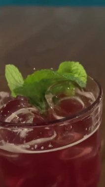 Şeffaf çaydanlıktan porselen fincana çay. Nane yaprağı ve böğürtlenli çaydanlıktan bardağa sıvı döküldü. Yüksek kalite 4k görüntü