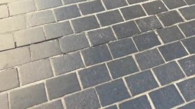 Döşeme taşlarının dokusu. Asfaltlı bir caddenin taşlarında yavaş dairesel hareketler. Şehir parkında kaldırım taşlarından yapılmış. 4k, çekim, yatay video, üst manzara, Krakow Polonya 'da kaldırım taşları