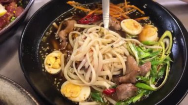 Erişteli ramen çorbası... udon yumurtaları... yeşil soğan sosu... siyah tabak üzerinde... lüks Asya mutfağı... miso çorbası... domuz göbekli lezzetli Ramen...