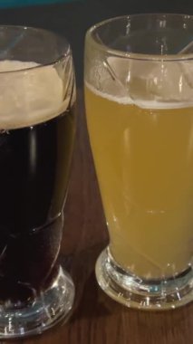 Bira, siyah arka planda baloncuklu iki bira bardağına dökülüyor. Köpüklü bira bardakları. Bokeh değişim ve hız rampası