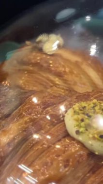 Taze hamur işi almak için kruvasan satan bir dükkan. Müşteri dikkatli bir şekilde taze hamur işleri ve taze kruvasanları tezgahtan alır. Dükkanda taze kruvasanlar var.. 