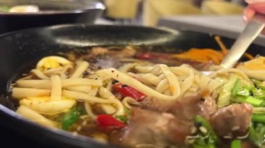 Erişteli ramen çorbası udon yumurtaları yeşil soğan sosu siyah tabakta susam sosu lüks Asya mutfağı miso çorbası sunumu.