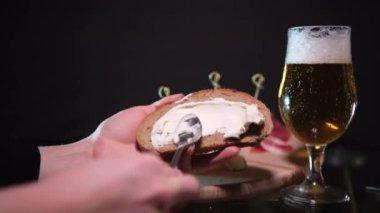 Parlak bir mutfakta aşçı kızarmış ekmeğe yumuşak Philadelphia peyniri sürer. Parlak bir mutfakta kadınların elleri kızarmış tostun üzerine yumuşak peynir ve tereyağı sürüyor. Yavaş çekimde yakın çekim, renkli.