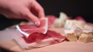 Pişmiş çiğ jambon, dönüyor. Bir dilim prosciutto Crudo, İtalyan yemeği. Domuz eti kurutulmuş jambon. Antipasto, salam. Brie prosciutto peyniri