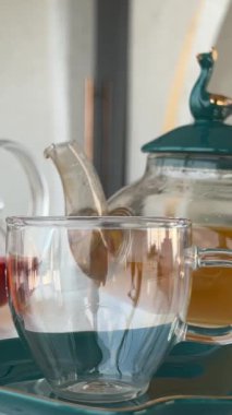 Bardaktan çaydanlığa limon ve otlarla sıcak çay dökerken yavaş çekim yapın. Sıcak ve rahat bir ortam. Yüksek kalite 4k görüntü
