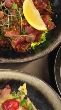 Biftekli salata, barbekü üzümü, Sezar salatası, marul, barbekü hindisi, pastırma ve ton balığı sosu. Erişteli ramen çorbası udon yumurtaları yeşil soğan soya sosu siyah tabakta susam